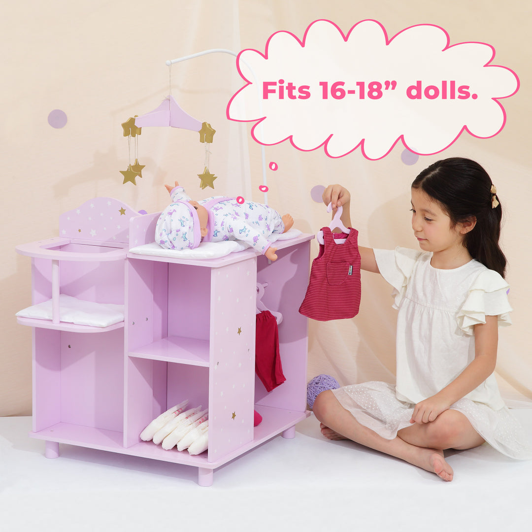 A little girl is sitting next to a baby doll changing station holding a red baby doll dress and a caption "Fits 16-18" dolls."