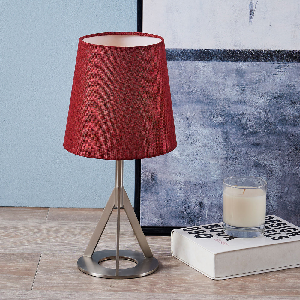 A Teamson Home Aria 15" Modern Table Lamp with Round Shade,Nickel/Red on a wooden table.