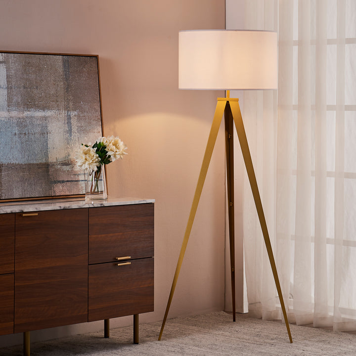 Floor lamp with a white shade on a Teamson Home Romanza 62" Postmodern Tripod base next to a wooden cabinet with a vase of flowers, near sheer curtains.