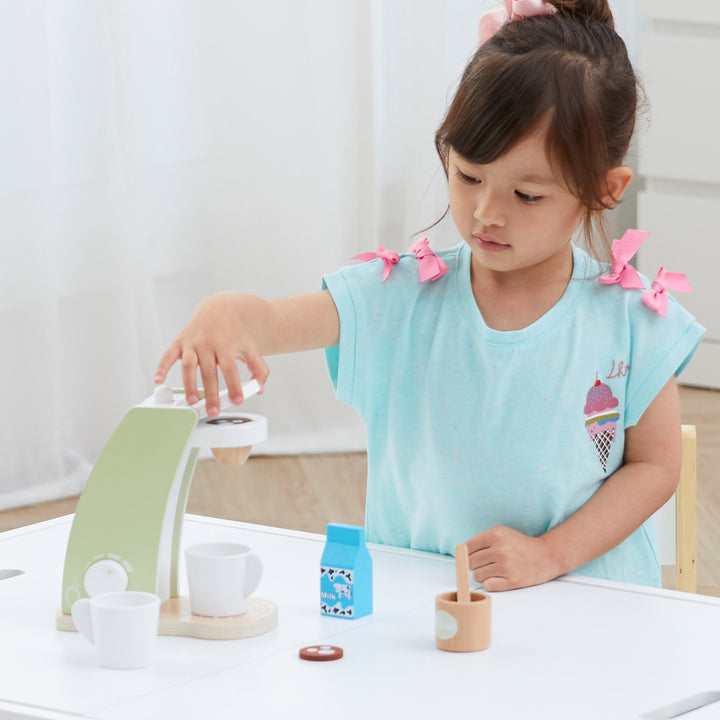 Teamson Kids - Little Chef Frankfurt Wooden Coffee machine play kitchen accessories is shown with a young girl adding coffee to the drip machine