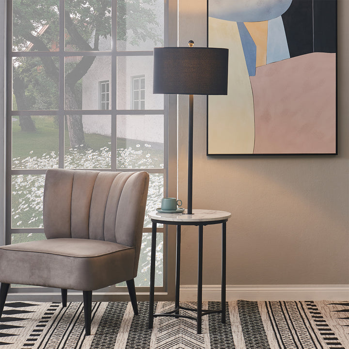 A Teamson Home Shenna Floor Lamp with Faux White Marble Tray Table, Black, next to a beige accent chair in front of a window