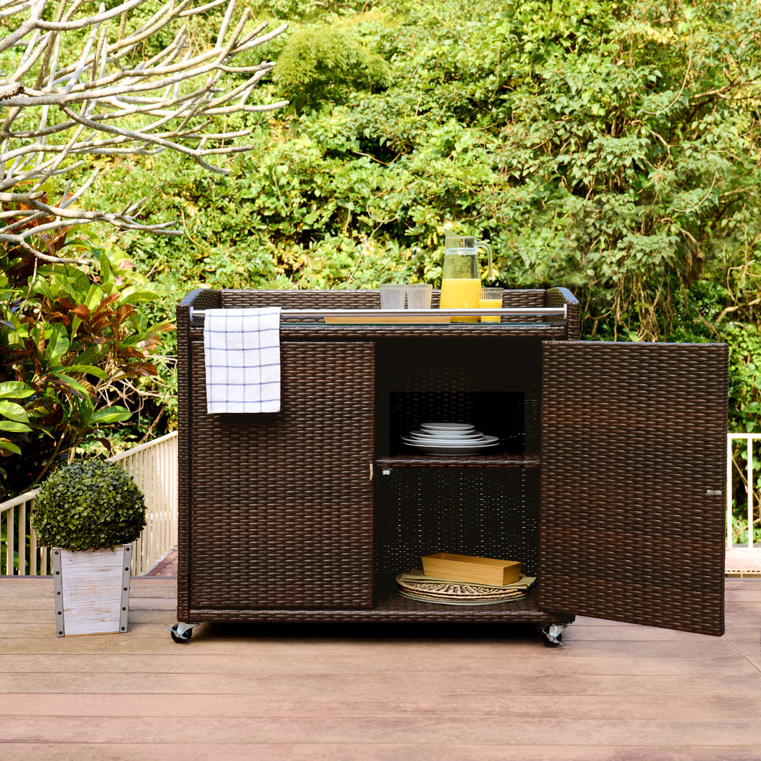 Teamson Home Veronica Portable Brown PE Rattan Outdoor Bar Cart with one of the doors open on a deck