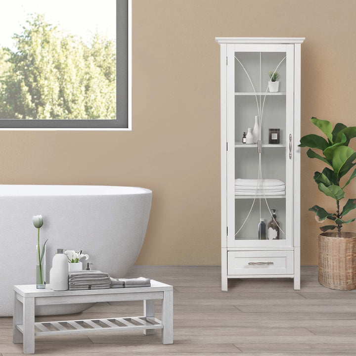 A modern bathroom interior with a freestanding bathtub, White Teamson Home Delaney Free Standing Tall Linen Cabinet Tower with Glass Panel Door with a Storage Drawer, and potted plant