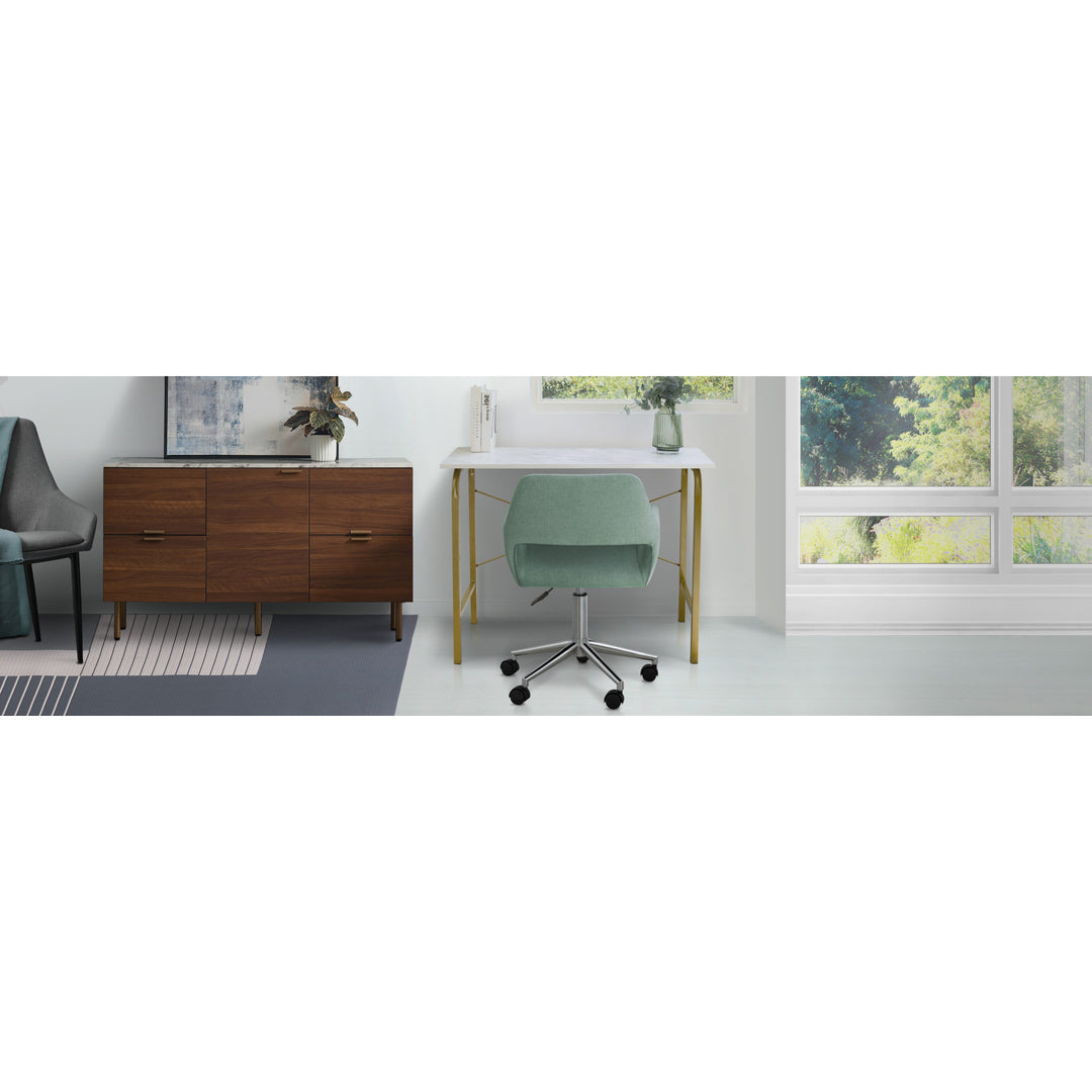 A Teamson Home Modern Fabric Office Chair with Adjustable Ergonomic Seat, Swivel Base, and Wheels, Mint/Chrome in a room with a desk and a window.