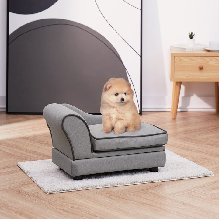 A Pomeranian sitting on a gray chaise lounge pet bed for cats or small dogs