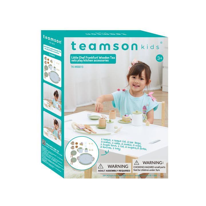 A young girl playing with a Teamson Kids Little Chef Frankfurt 20 Piece Wooden Play Kitchen Tea Party Set, Green displayed on the box at her kids' tea party.