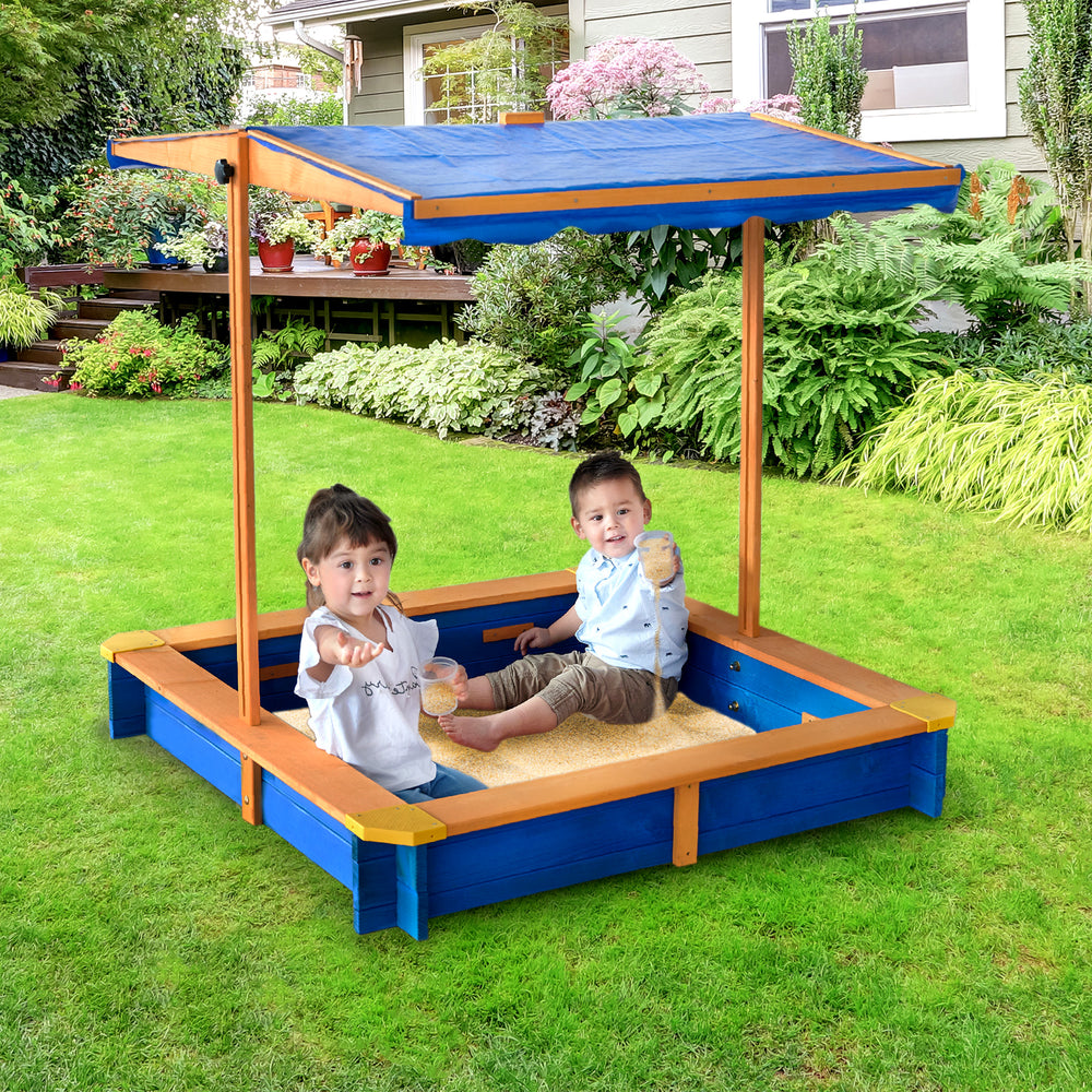 Two children sitting inside and playing in the Teamson Kids 4' Square Solid Wood Sandbox with Rotatable Canopy Cover, Honey/Blue