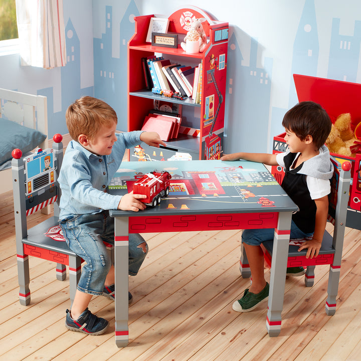 A boy with blonde hair and a boy with brown hair sit across from each other in a firemen-themed room at a firemen themed table.