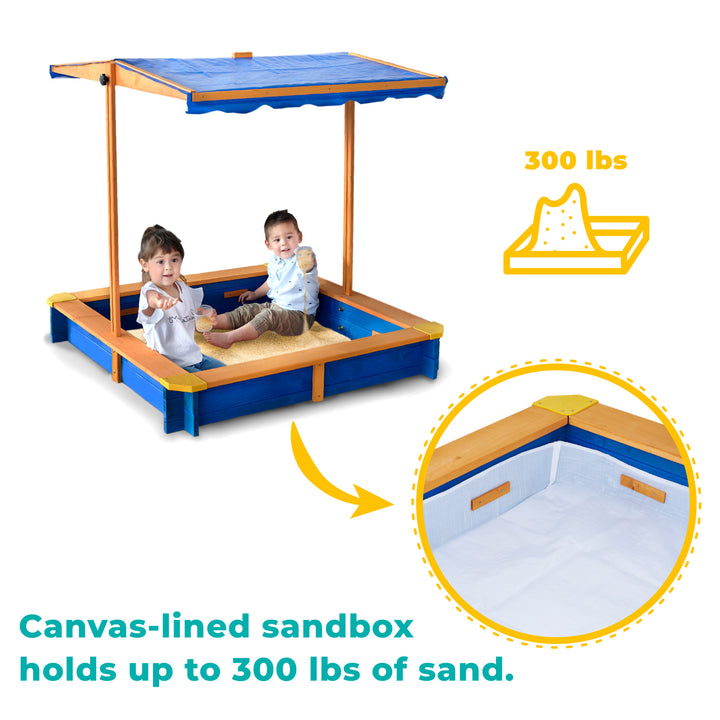 Two children sitting in a Teamson Kids 4' Square Solid Wood Sandbox with Rotatable Canopy Cover, Honey/Blue, which can hold up to 300 lbs of sand.
