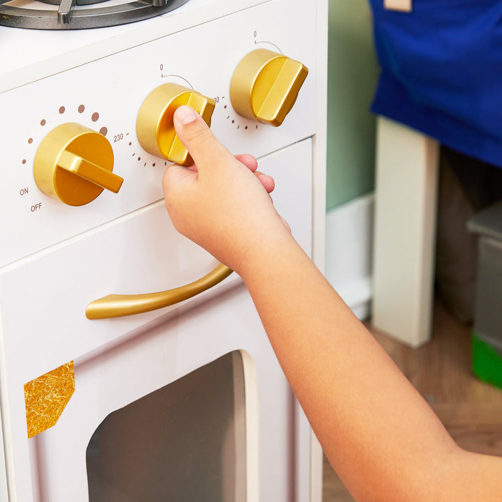Close-up of gold-colored  knobs that twist and  make noise on a play kitchen.