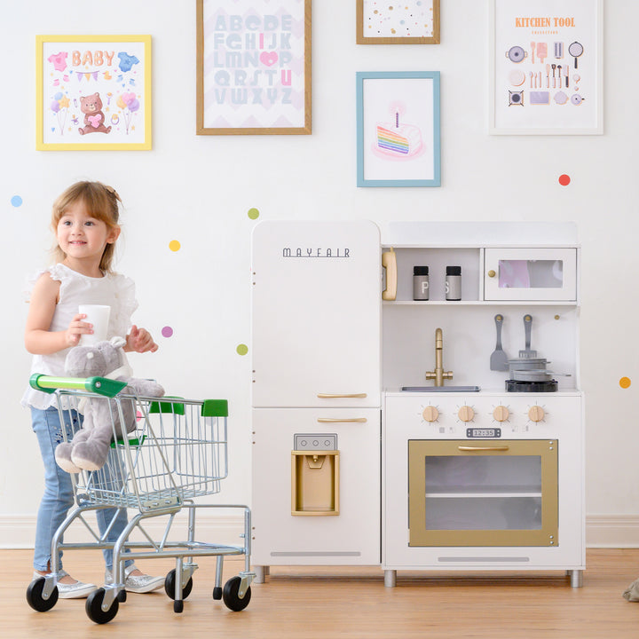 A young girl enjoys interactive features while playing with a Teamson Kids Little Chef Mayfair Classic Kids Kitchen Playset with 11 Accessories in a colorful room with kid-sized dimensions.