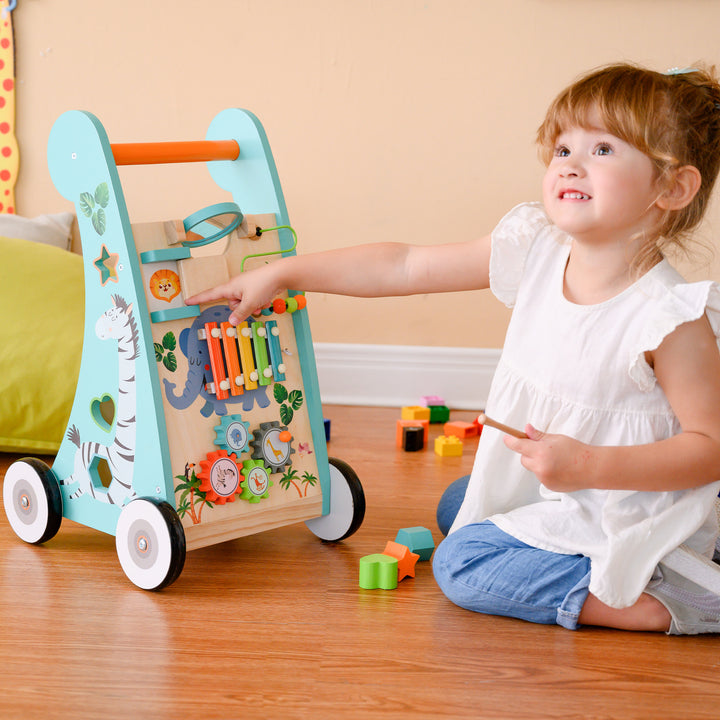 A little girl points to the lion illustration behind the door on the front of the baby walker and activity station.