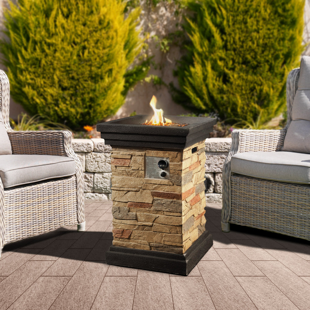 Teamson Home 20" Outdoor Square Faux Slate Propane Gas Fire Pit between two wicker armchairs on a patio.