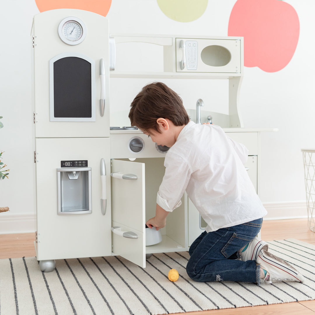 A child playing with a Teamson Kids Little Chef Westchester Retro Kids Kitchen Playset, Ivory that includes interactive features.