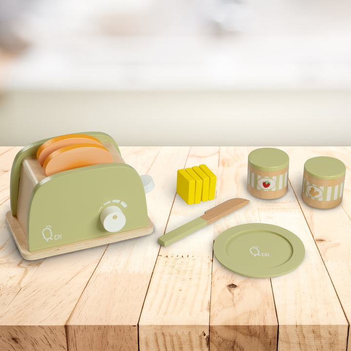 A Teamson Kids Little Chef Frankfurt Wooden Toaster and utensils on a wooden table for kids' play kitchen.