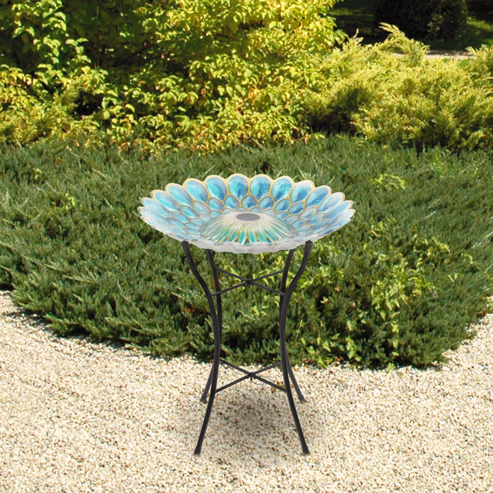 Teamson Home 18" Solar Fusion Glass Birdbath standing on a black metal frame in a garden setting.