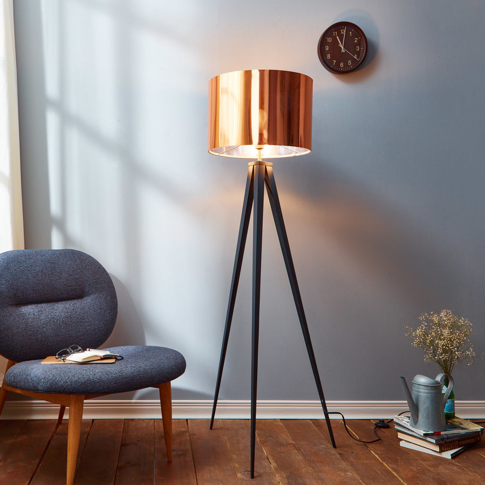 Teamson Home Romanza 60.23" Postmodern Tripod Floor Lamp with Drum Shade, Matte Black/Copper with a copper shade next to a blue armchair and small side table in a cozy room corner.