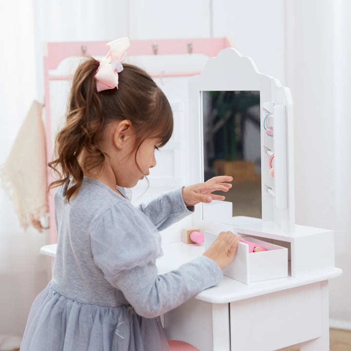 A little girl opening the storage drawer on the white vanity table.