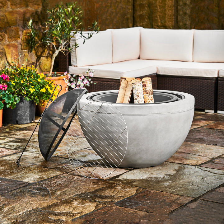 Modern Teamson Home 30" Outdoor Round Wood Burning Fire Pit with Faux Concrete Base, Gray with firewood on a patio, doubling as outdoor decor.
