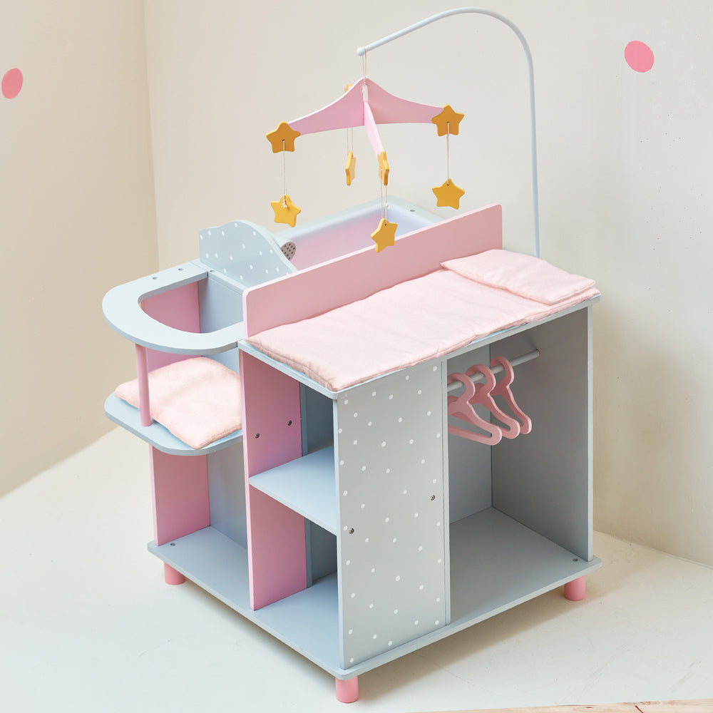 A baby doll changing station in pink and gray with white polka dots with a closet, storage shelves, high chair, mobile, sink, and changing table.