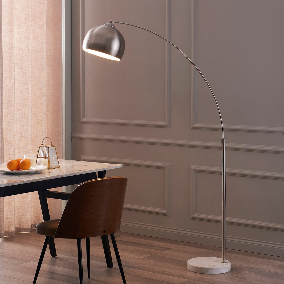 This Teamson Home Arquer Arc 68" Metal Floor Lamp with Bell Shade, Polished Nickel next to a table is the perfect lighting solution.