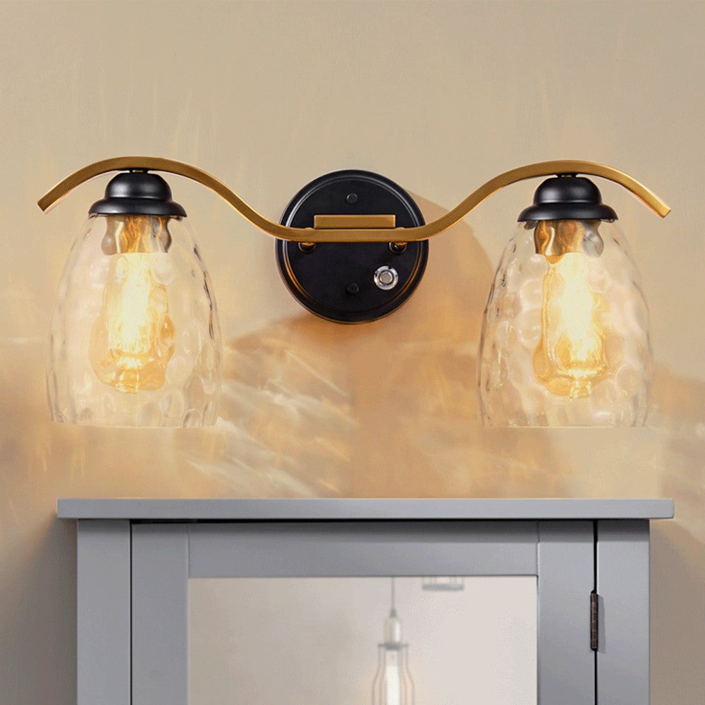 Heidi 2-Light Bathroom Vanity Wall Sconce Light with 3-Stage Touch Dimmer & Clear Hammered Glass Cloche Shades, Black/Brass with brass arms.