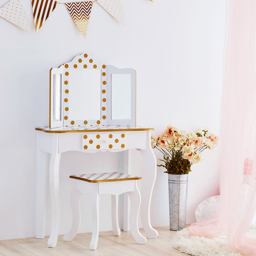A girl's bedroom with a Teamson Kids Gisele Polka Dot Vanity Playset, White / Gold dressing table and a mirror.