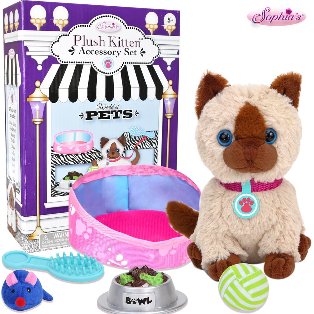 A play siamese kitten with a pink collar and blue tag, a blue toy mouse, a blue brush, a bowl of faux food, a green and white ball, a pink mat and a pink pet bed and the packaging it comes in.