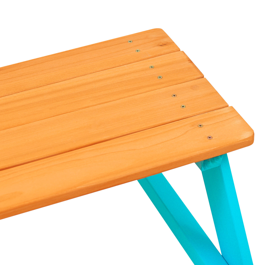 Close up corner photo of the Teamson Kids Child Sized Wooden Outdoor Picnic Table, Warm Honey/Aqua against a white background.