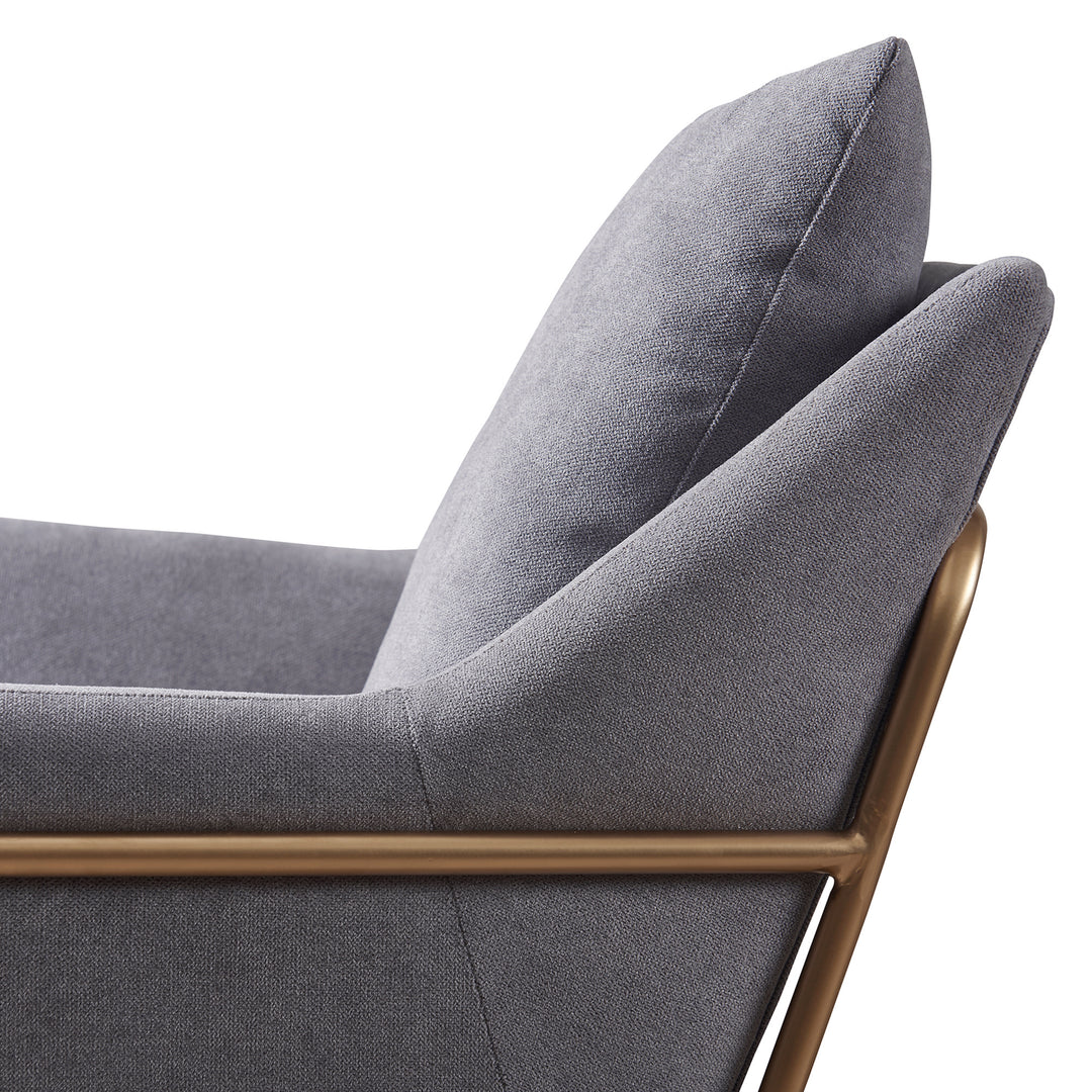 A side view of the Miller gray armchair and ottoman with gray fabric and gold framework.