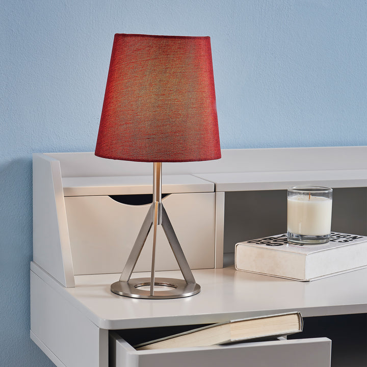 A Teamson Home Aria 15" Modern Table Lamp with Round Red Shade and a geometric nickel base on a white writing desk.