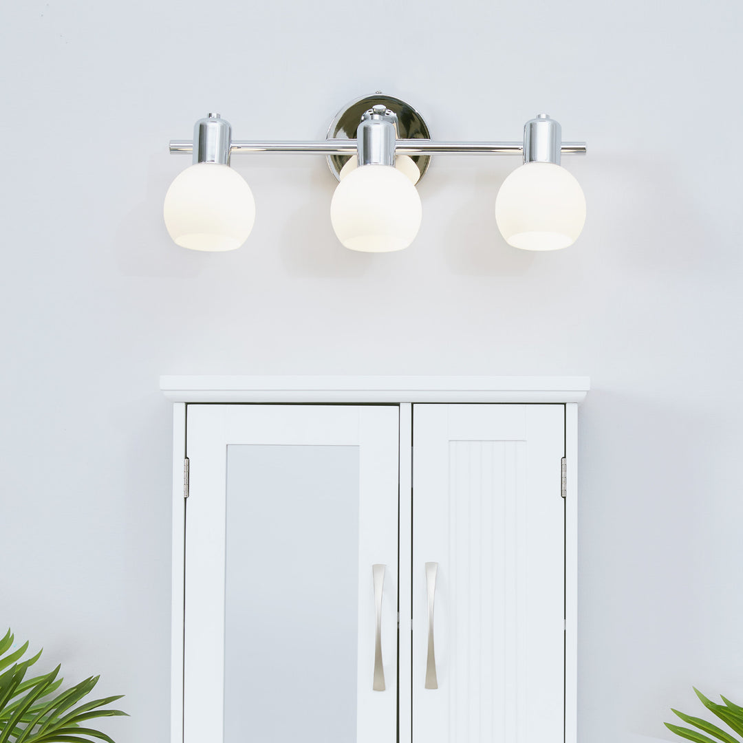 Teamson Home  3-Light Vanity Fixture with Frosted Globe Shades, Chrome above a medicine cabinet