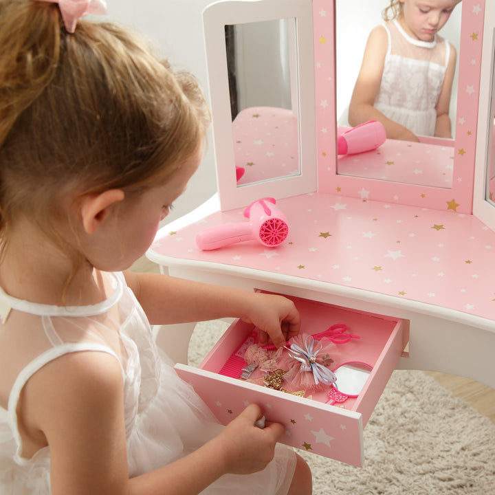A little girl with a Fantasy Fields Gisele Play Vanity Set with Mirrors, Pink/White.