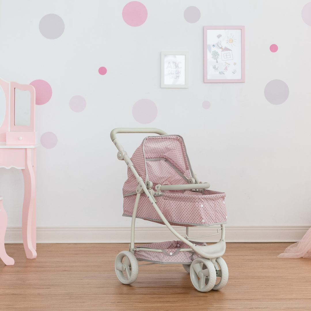 A Olivia's Little World Polka Dots Princess 2-in-1 Baby Doll Stroller with an adjustable handle and convertible shape in a room with a pink vanity table.