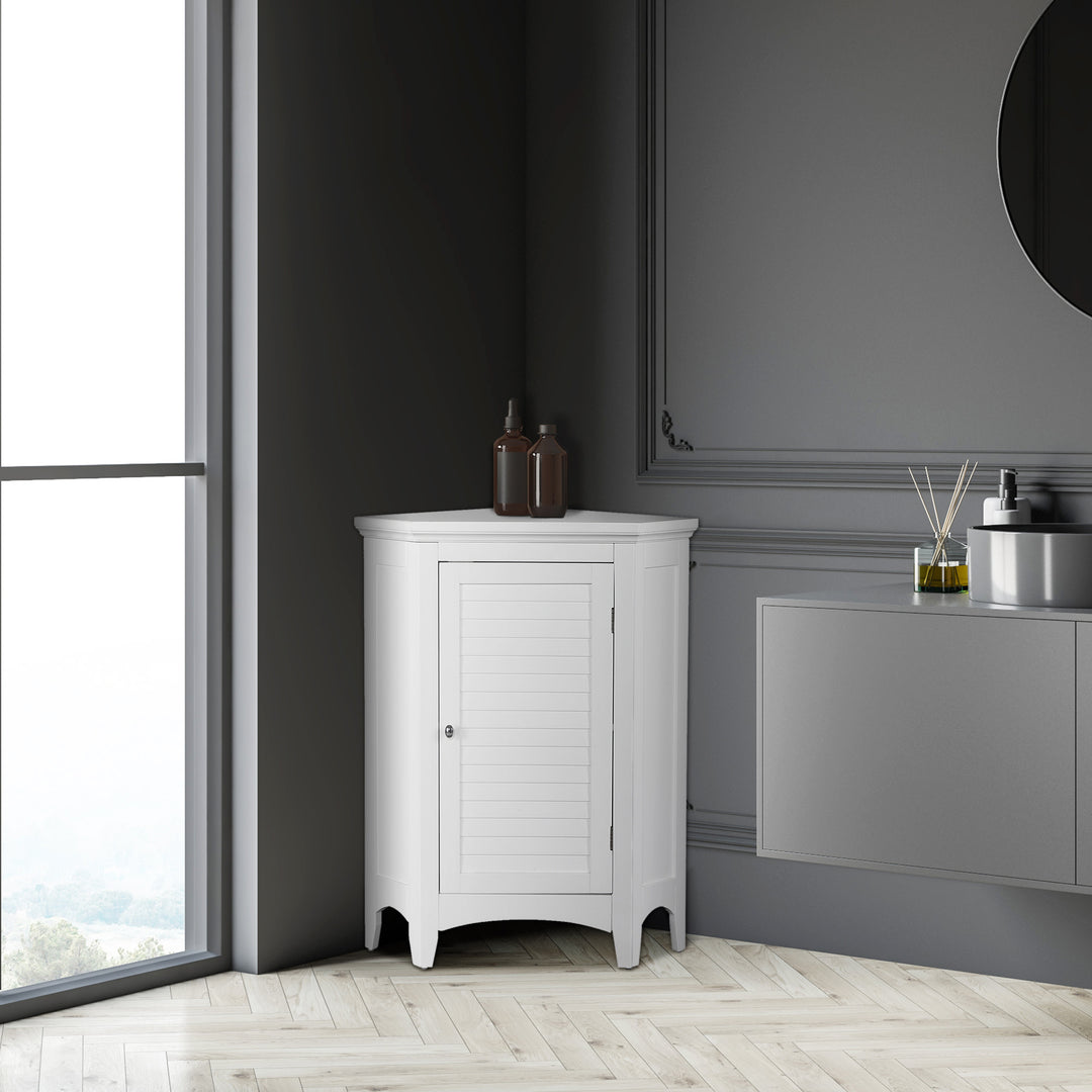 White Glancy Corner Floor Cabinet with Louvered Door, Chrome Knob stands against a gray wall near a window, complementing a modern minimalist interior.