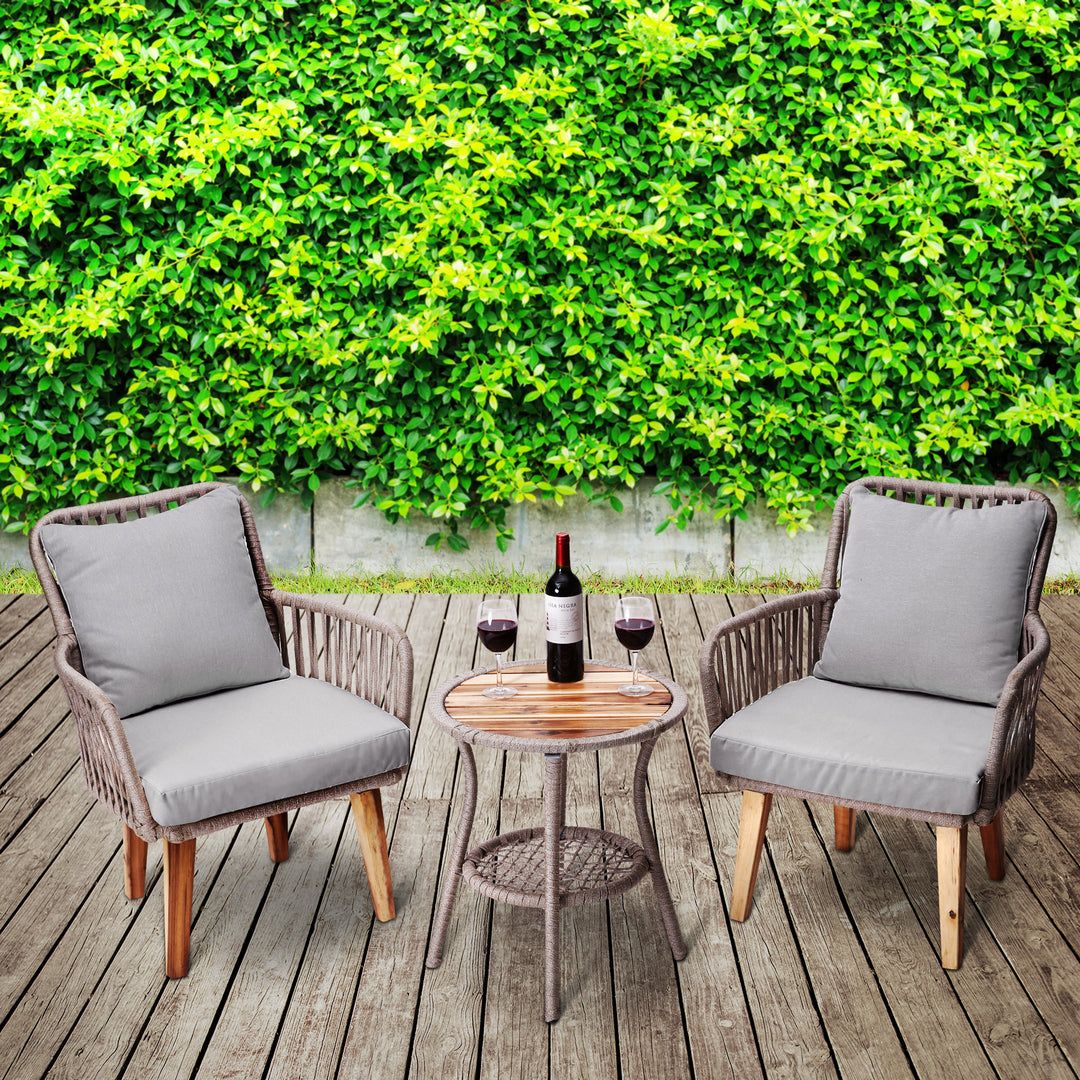 Teamson Home 3-Piece Rope & Acacia Wood Patio Set, Gray & Natural up against shrubbery