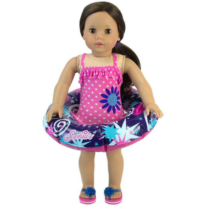 An 18" doll with brunette hair and brown eyes is wearing a pink ruffled polka dot bathing suit with an inflatable print innertube around her waist.