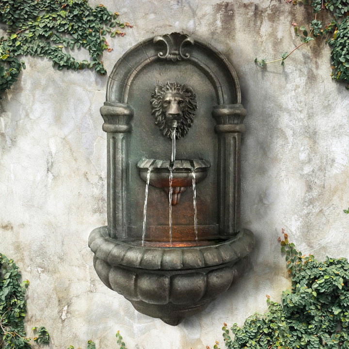 Teamson Home Outdoor Tiered Lion Head Wall Water Fountain mounted on a stone wall with ivy around it