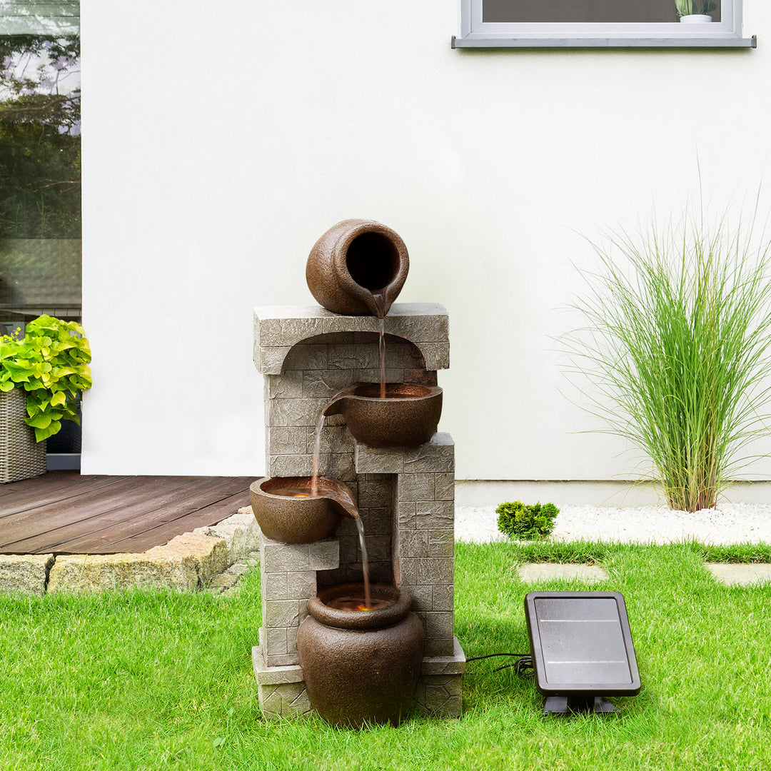Teamson Home Solar Powered 4-Tier Cascading Bowls Water Fountain, brown with a solar panel outside of a home in the yard