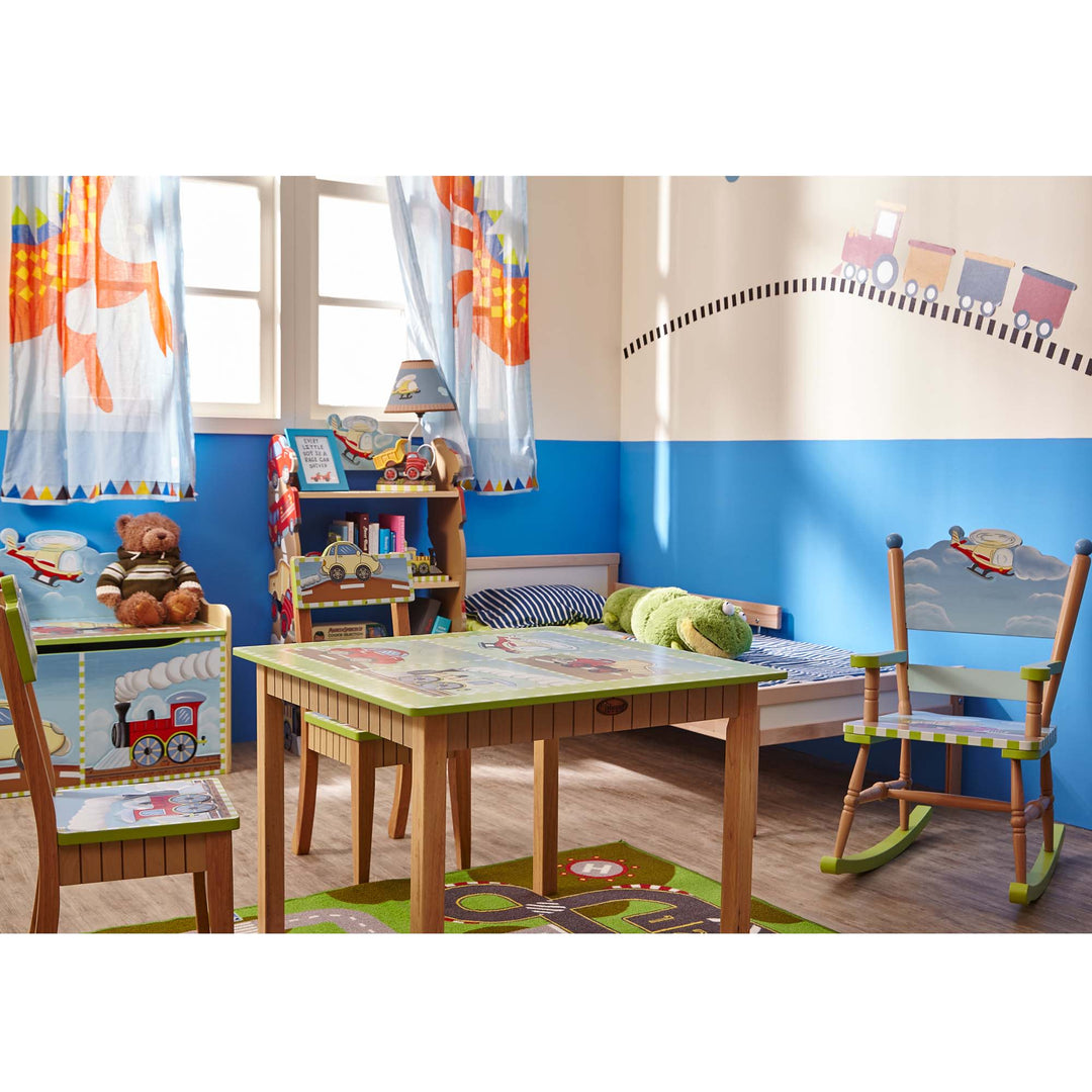 A children's room with a train table, chairs, and a Fantasy Fields Kids Transportation Themed Wooden Bookshelf with Storage Drawer, Multicolor.