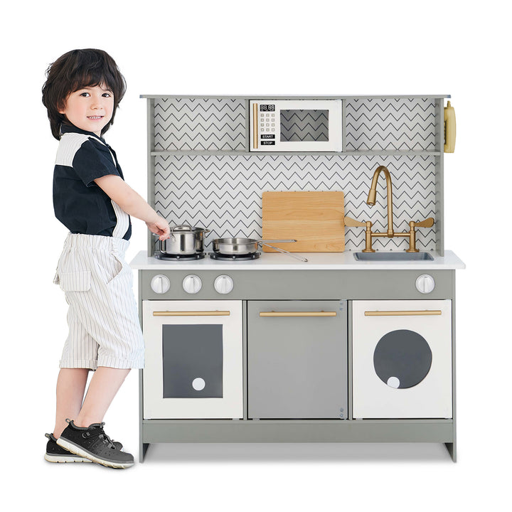 A young child playing with a Teamson Kids Little Chef Berlin Modern Play Kitchen with 6 Accessories, Gray/White that includes interactive features.