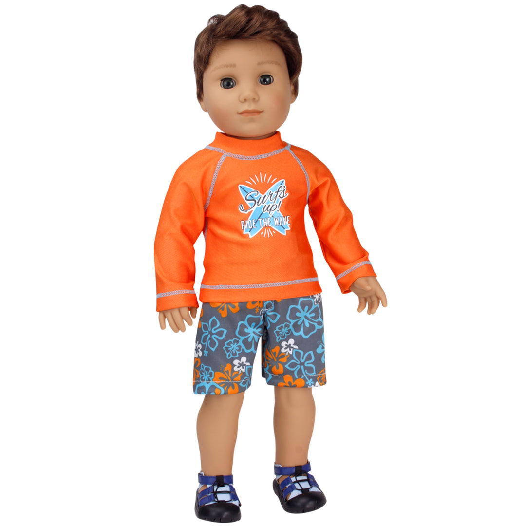 An 18" boy doll with brunette hair and brown eyes wearing an orange rash guard and blue and gray floral surf shorts.