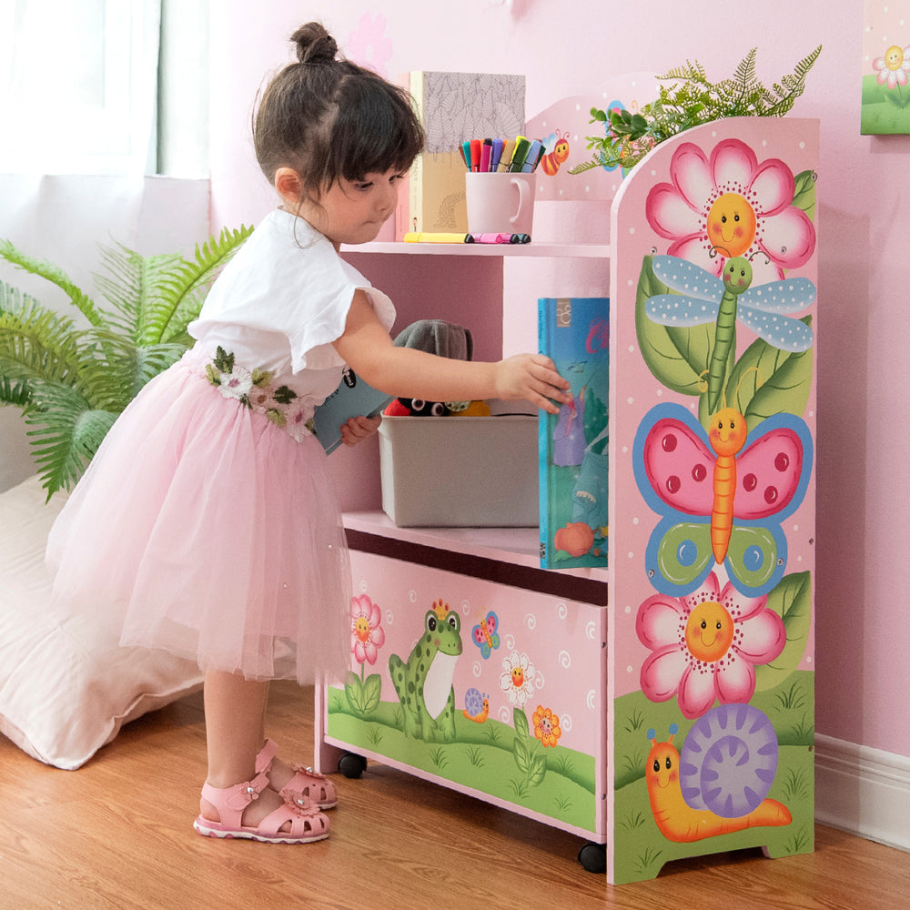 A little girl in a pink tutu standing next to a Fantasy Fields Magic Garden Kids Wooden Toy Organizer with the illustrations in full view.