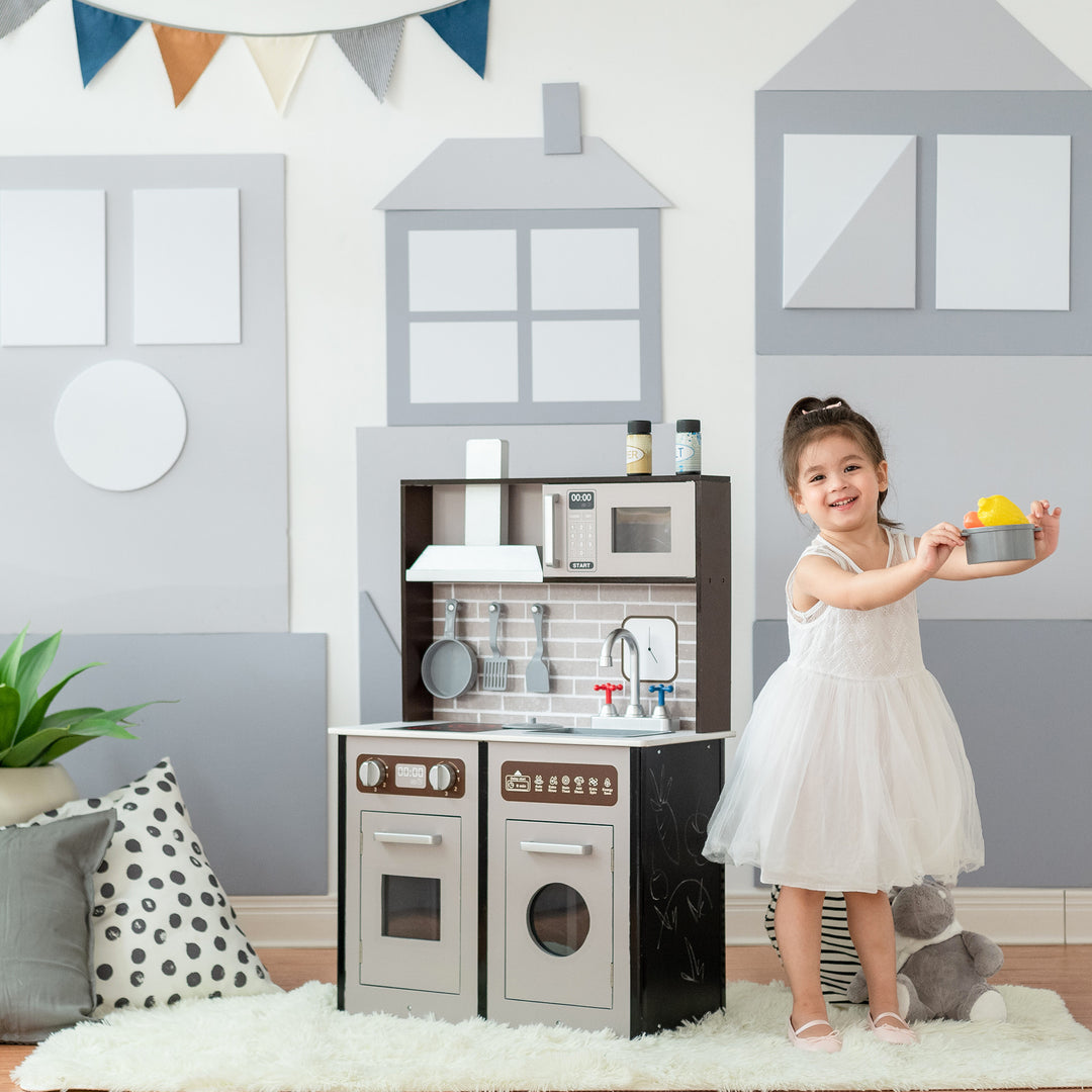 A young girl playing with a Teamson Kids Little Chef Burgundy Classic Play Kitchen in a room decorated with house-themed wall decals, featuring realistic details.