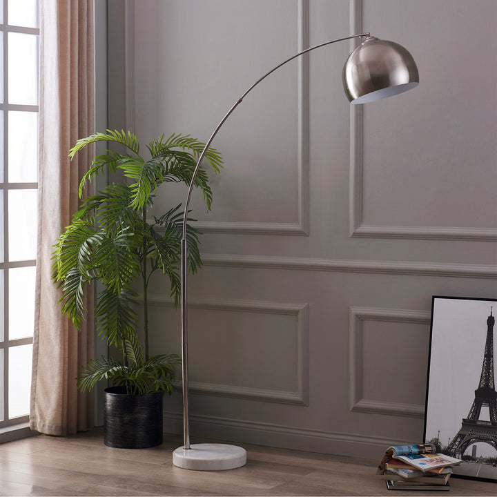 A Teamson Home Arquer Arc 68" Metal Floor Lamp in a living area with the Eiffel Tower in the background. The Arquer Floor Lamp stands at 68 inches tall and is only 12.6 inches wide; its bellshade complements any modern living space.