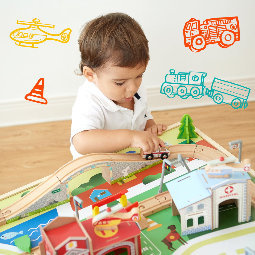 A little boy pushing a white ambulance down the train tracks behind the hospital with icons of a traffic cone, helicopter, fire truck, and train illustrated around his head.
