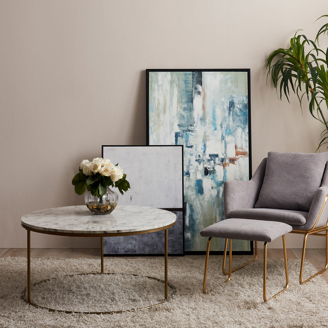 A living room with a Teamson Home Marmo Modern Marble-Look Round Coffee Table, chairs, and a painting.