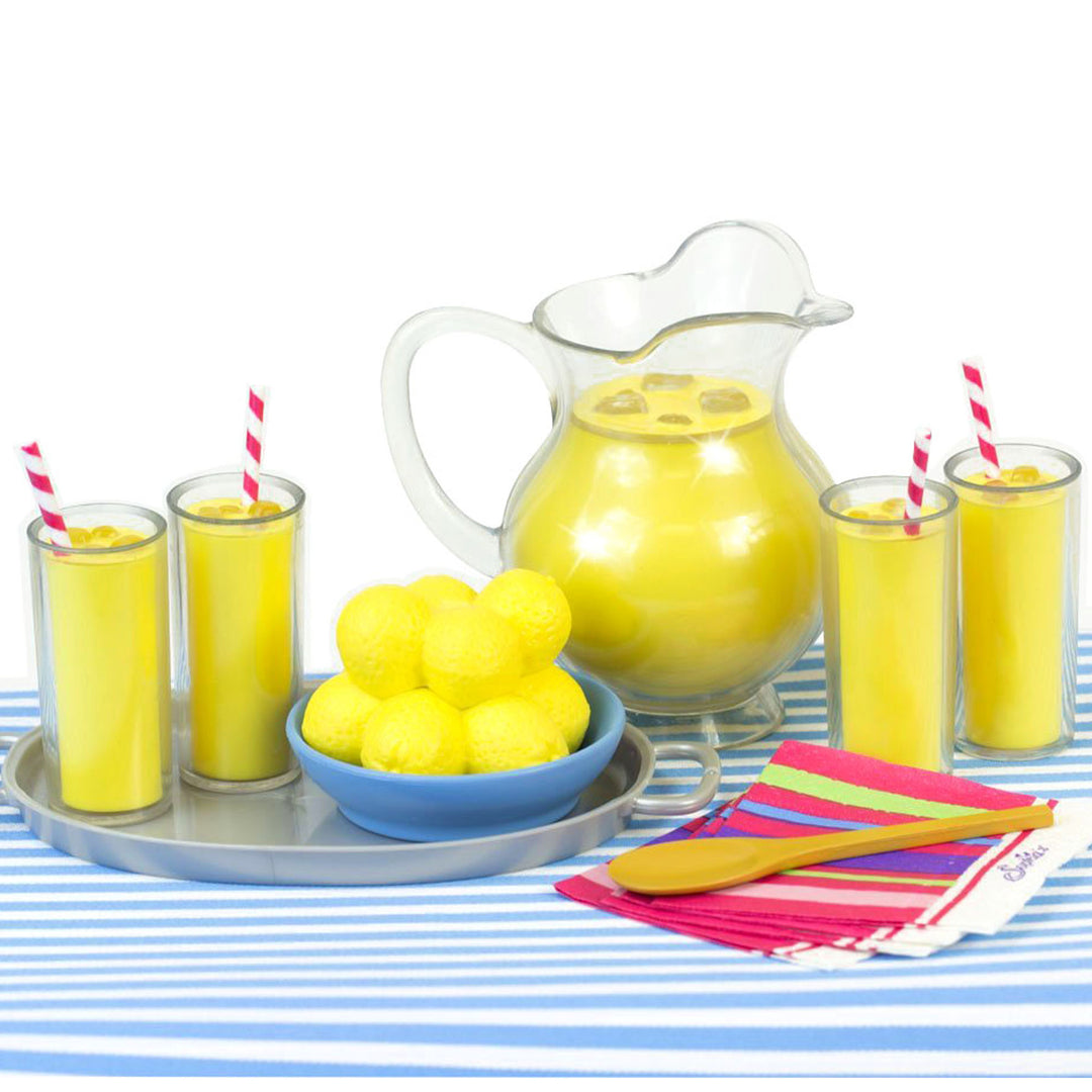 Four glasses of pretend lemonade with ice cubes and straws, napkins, a bowl of lemons and a pitcher of lemonade.