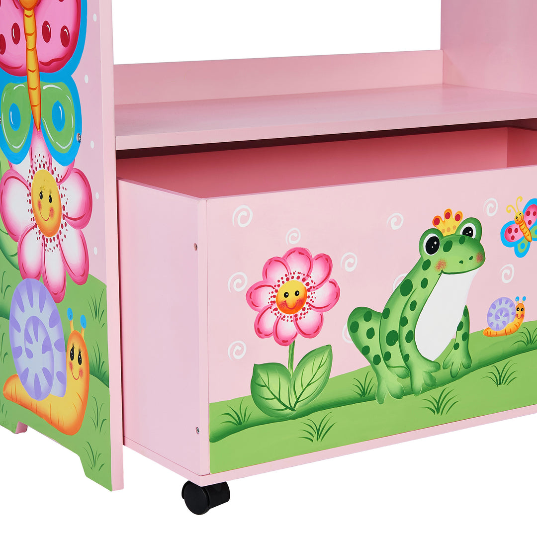 A view of the storage drawer opened underneath the bottom shelf of the pink toy organizer with flowers, snails, butterflies and a frog illustrated.